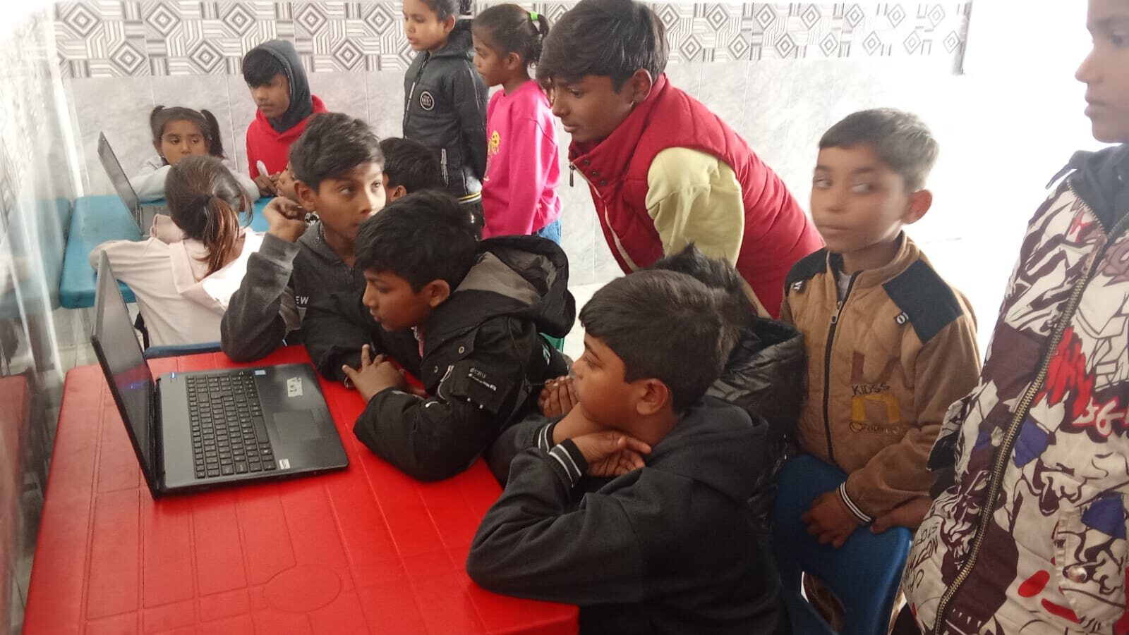 Meri Pehchan students gathered around a laptop during a lesson about children’s rights