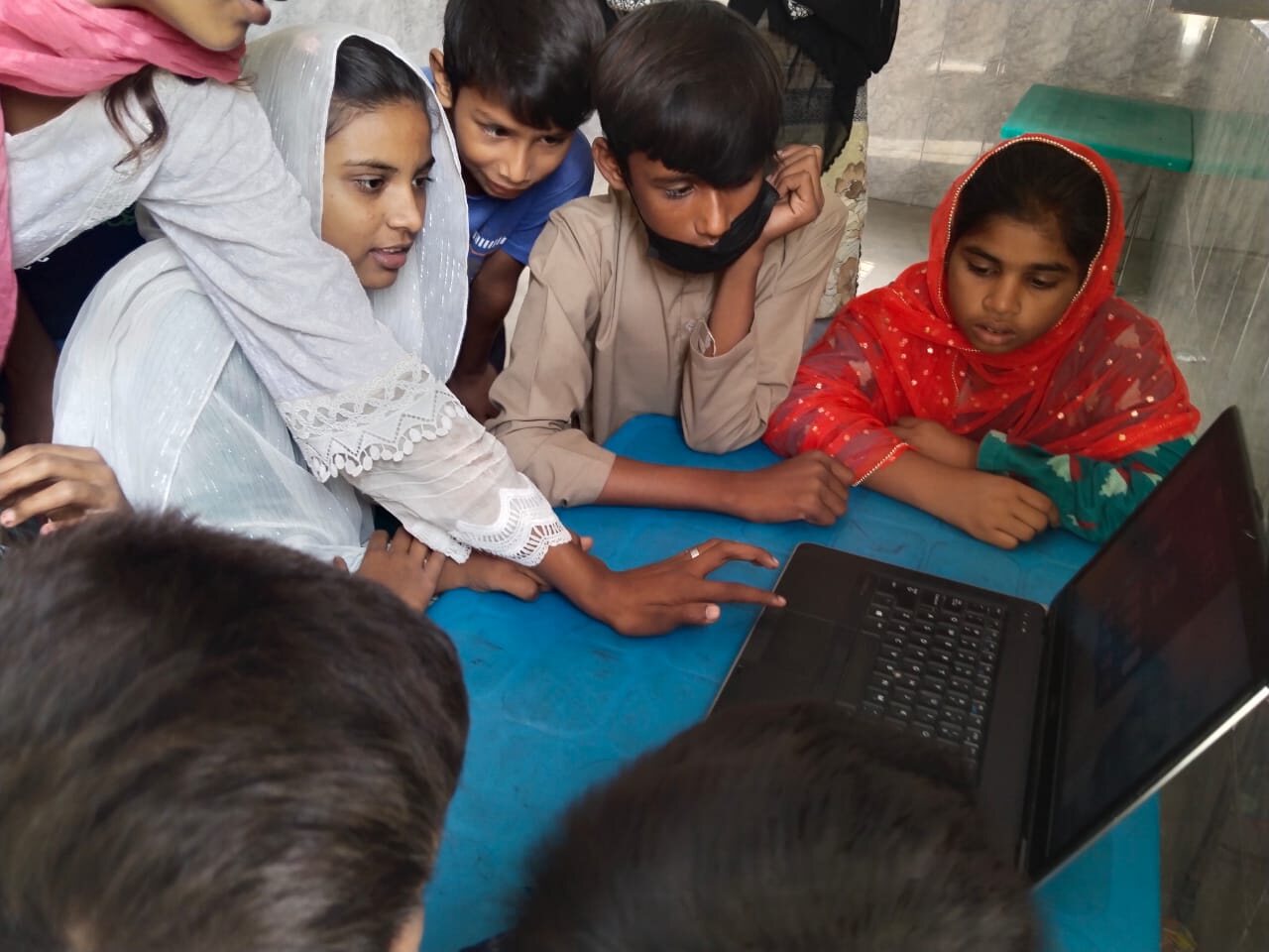 Meri Pehchan students collaborating around a computer in a small learning group