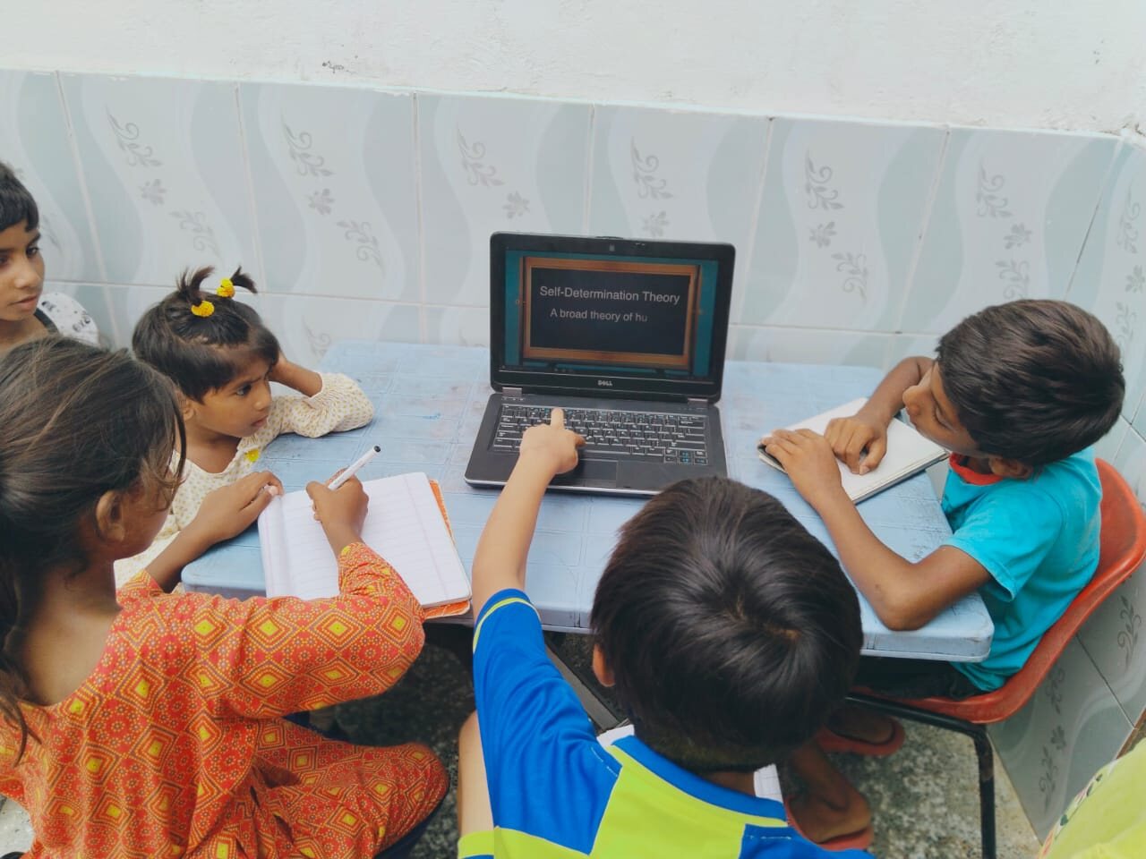 Meri Pehchan students working together around a laptop with notebooks